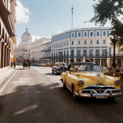 Ein gelber Oldtimer fährt durch die Straßen von Havanna